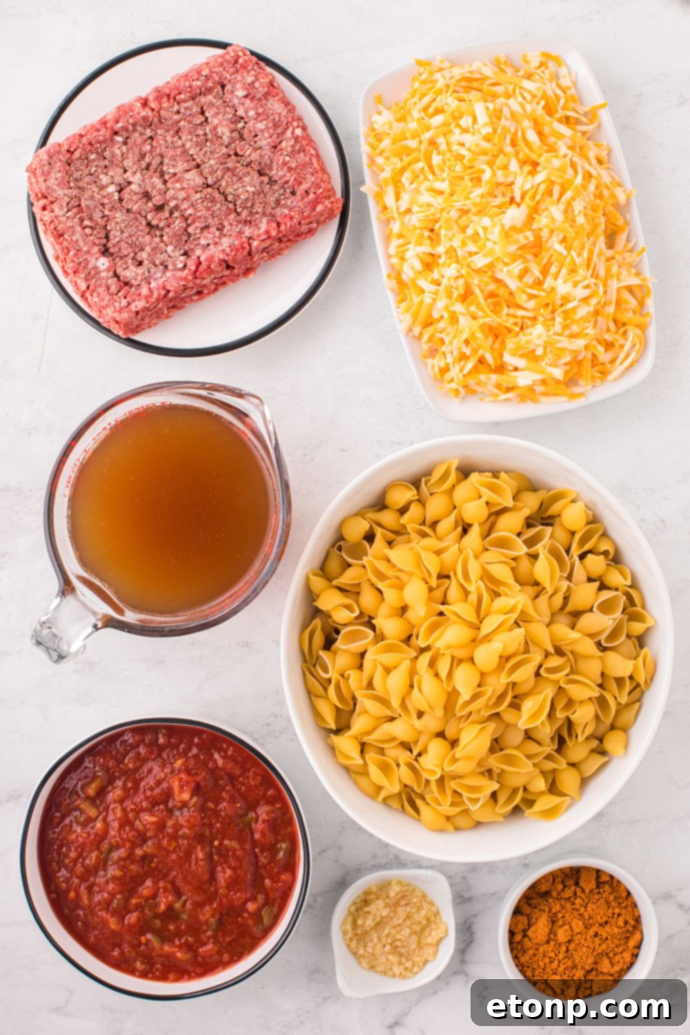 Cheesy Taco Pasta 8 Bowls of raw ground beef, dry pasta, and other ingredients arranged on a counter, ready for cooking taco pasta.