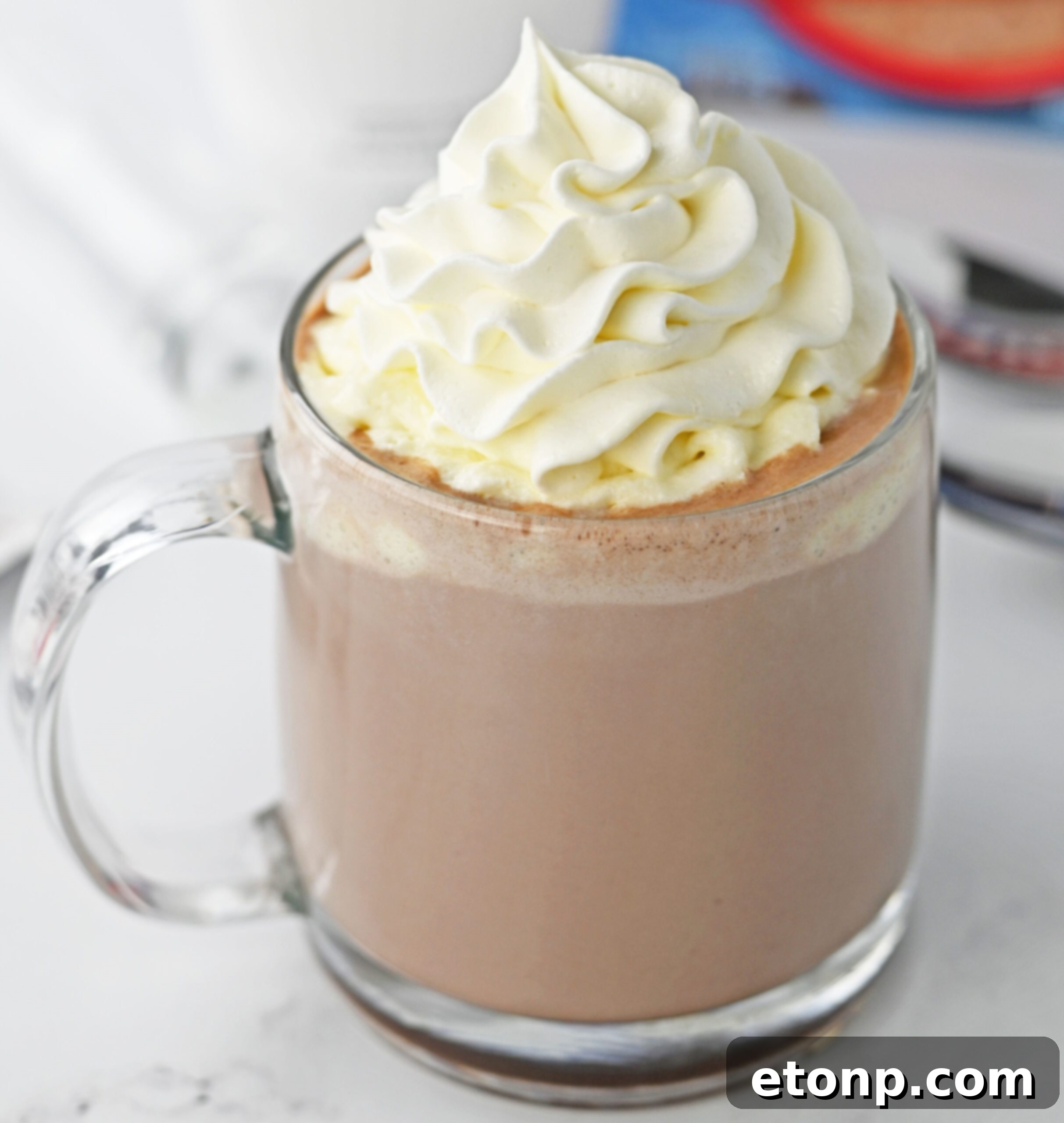 up close shot of a hot chocolate rumchata in a clear glass mug topped with whipped cream