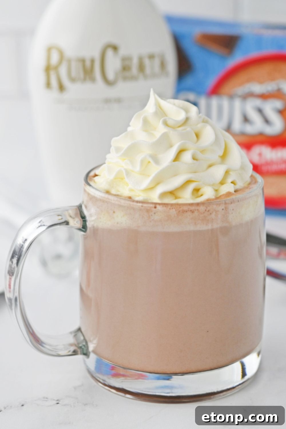 close up of hot chocolate with whipped cream on counter with a bottle of RumChata in the background 