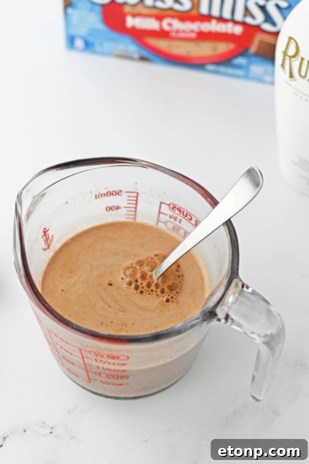 mixing hot chocolate in a measuring cup on table 