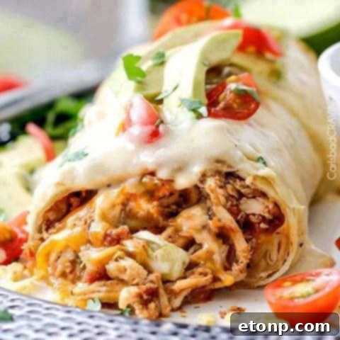 Smothered Baked Chicken Burritos, topped with a creamy sauce and melted cheese.