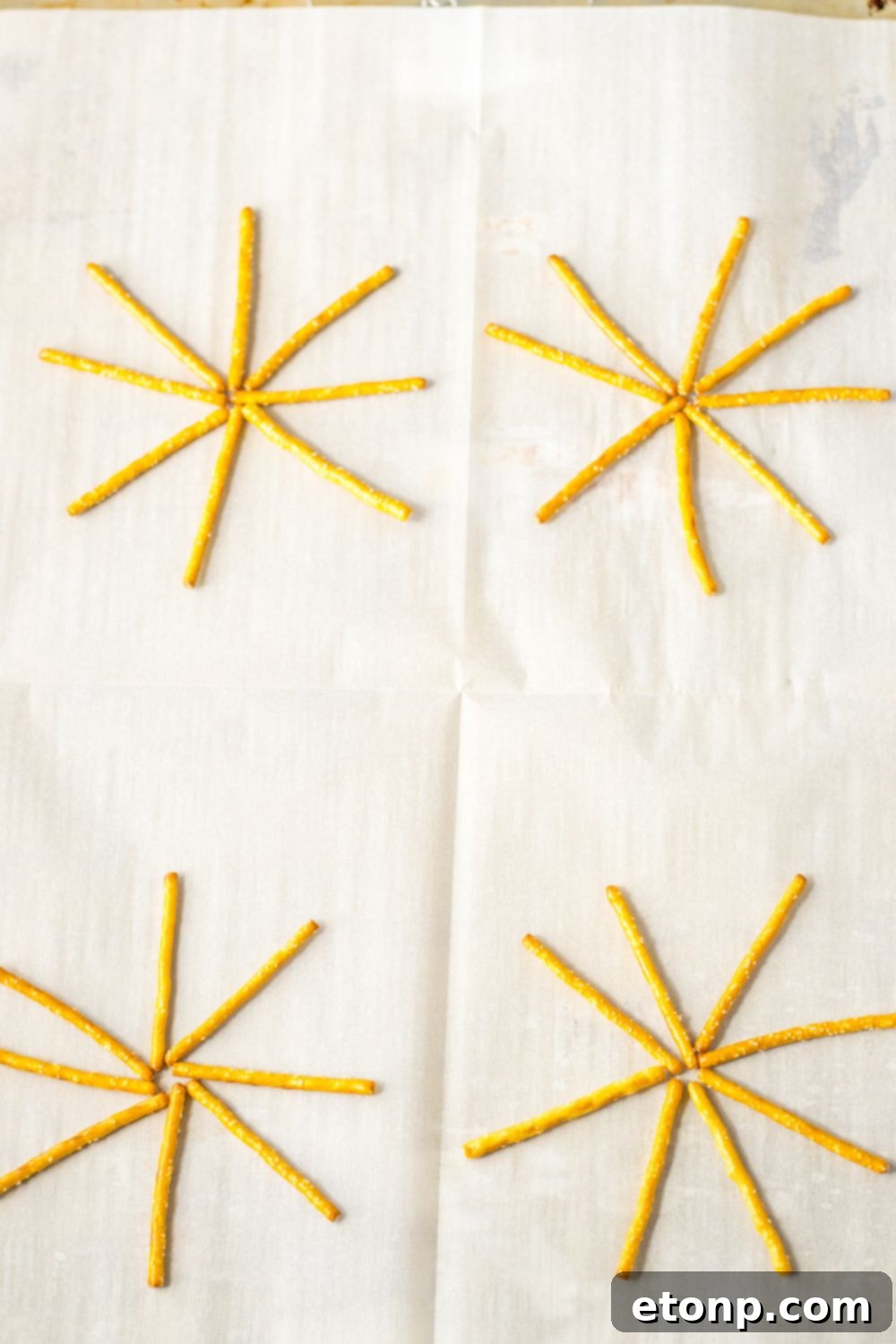 Pretzels spread out on parchment paper lined baking sheet, ready for decoration