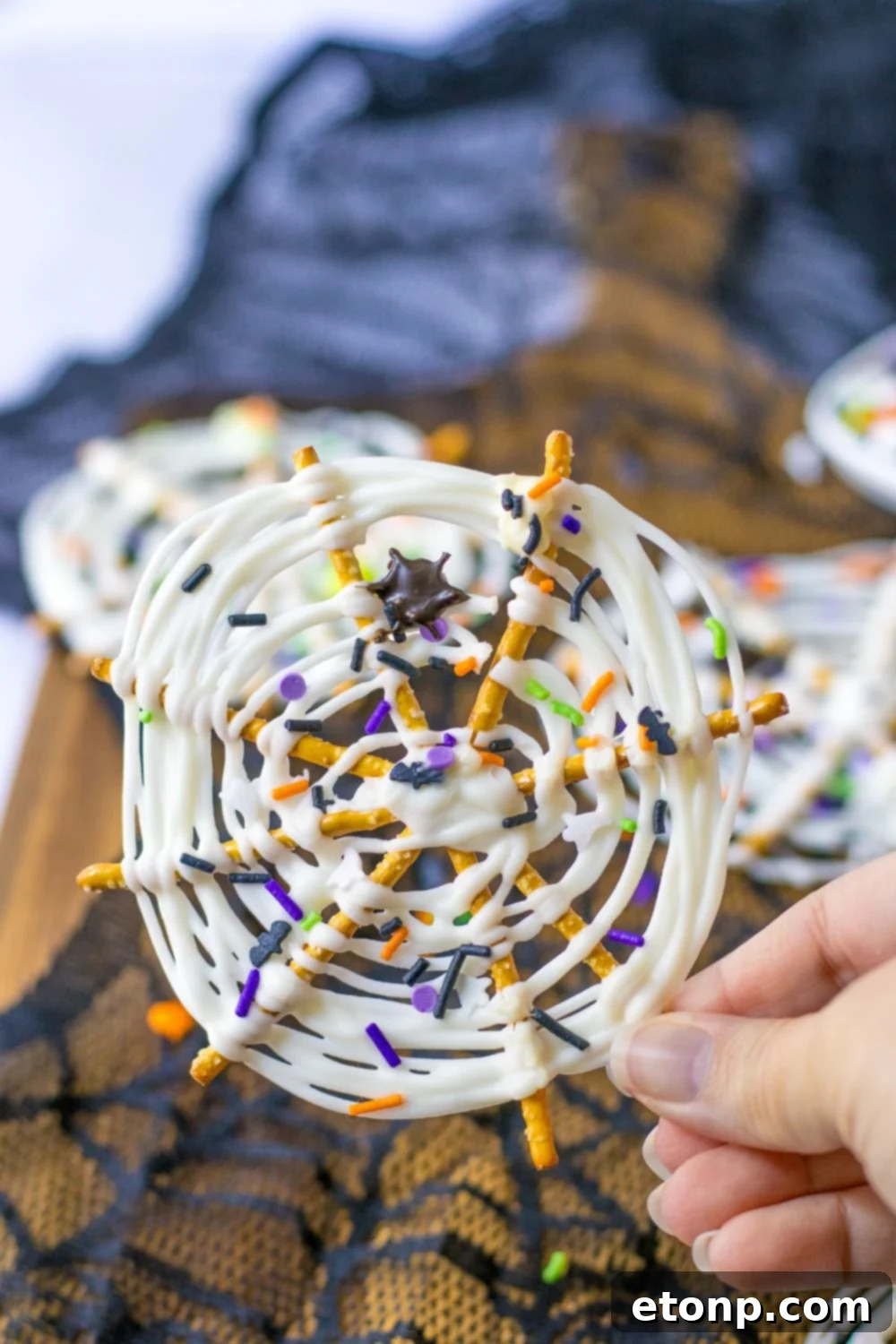 A hand holding a decorated Halloween pretzel