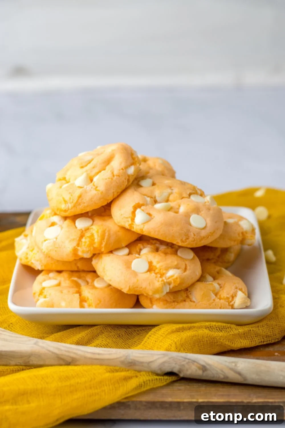 orange cream cookies stacked on a plate with orange towel under it