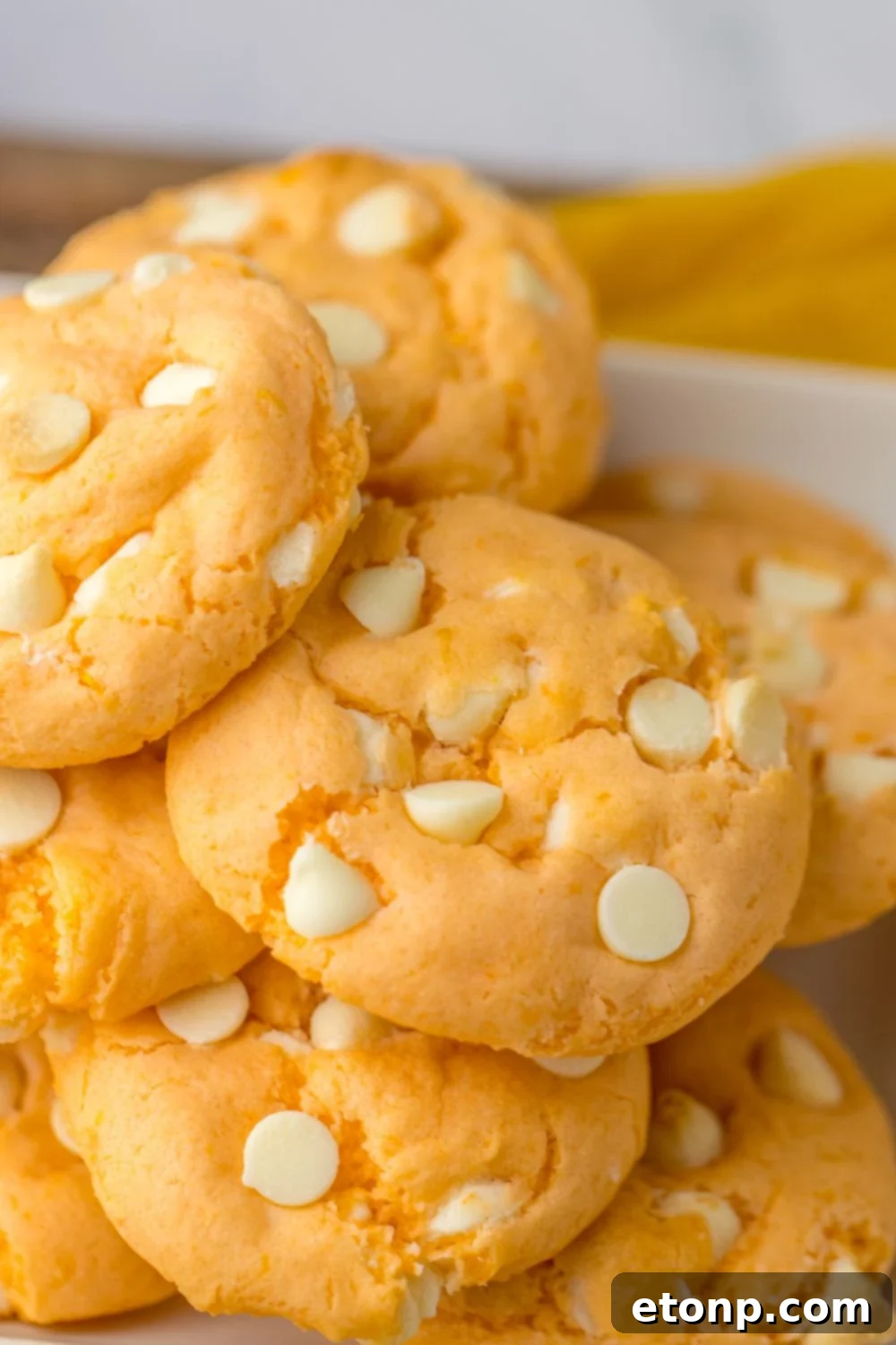 orange zest cookies stacked on top of each other on tray
