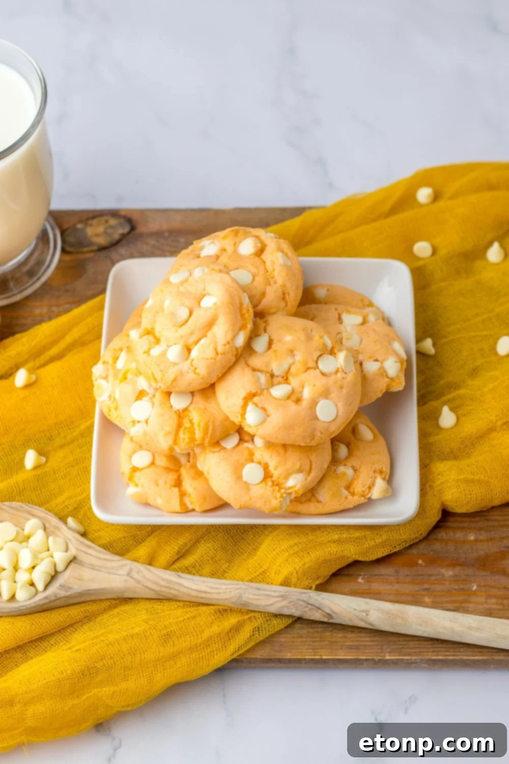 overhead view of orange cookies on tray with a wooden spoon with chocolate chips in it