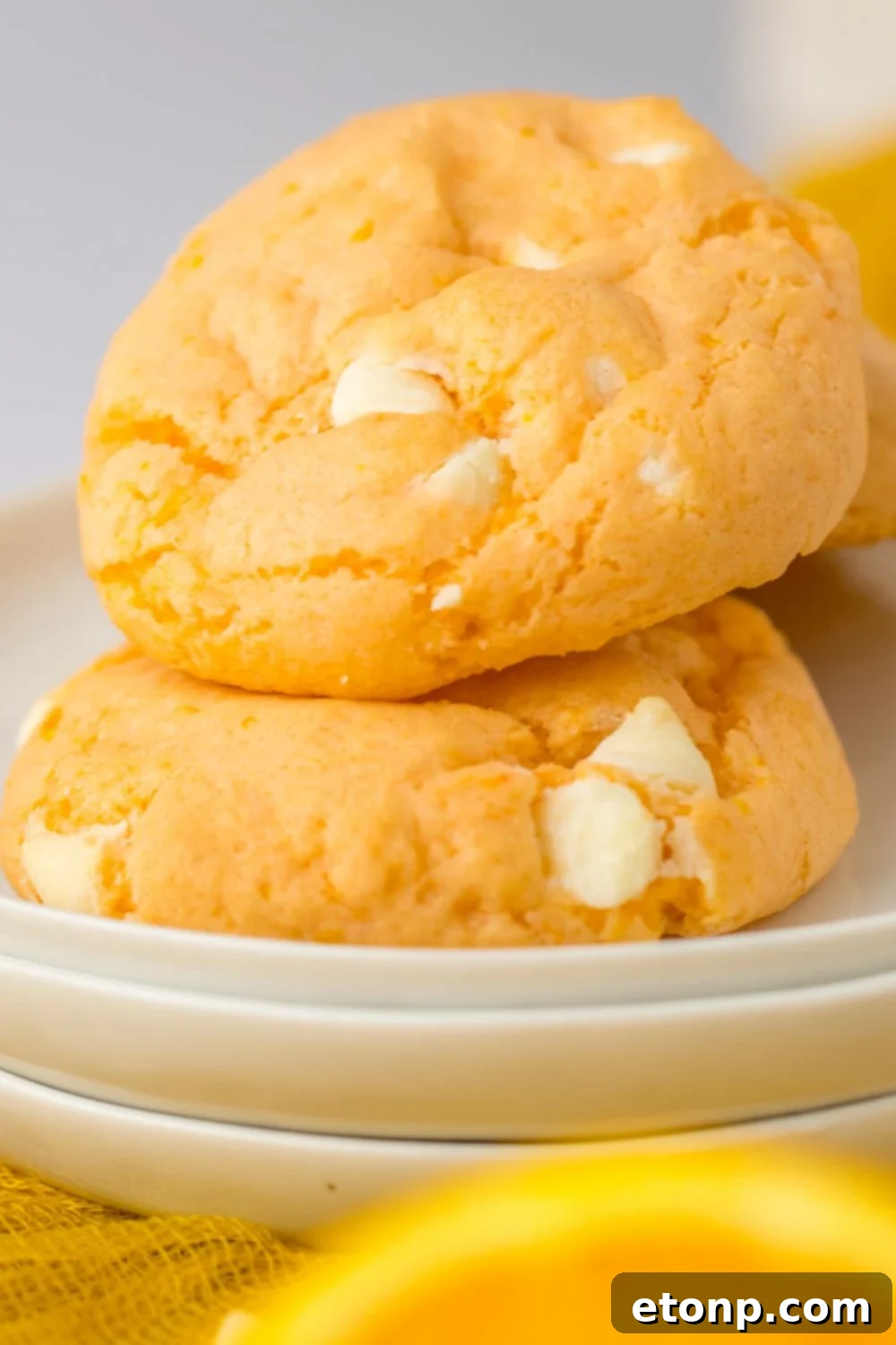 orange creamsicle cookies stacked on a set of plates with an orange sitting in the front