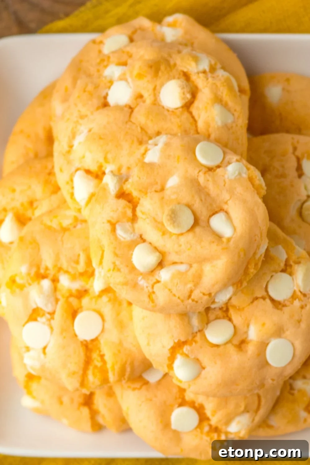 orange creamsicle cookies stacked on a white plate sitting on table