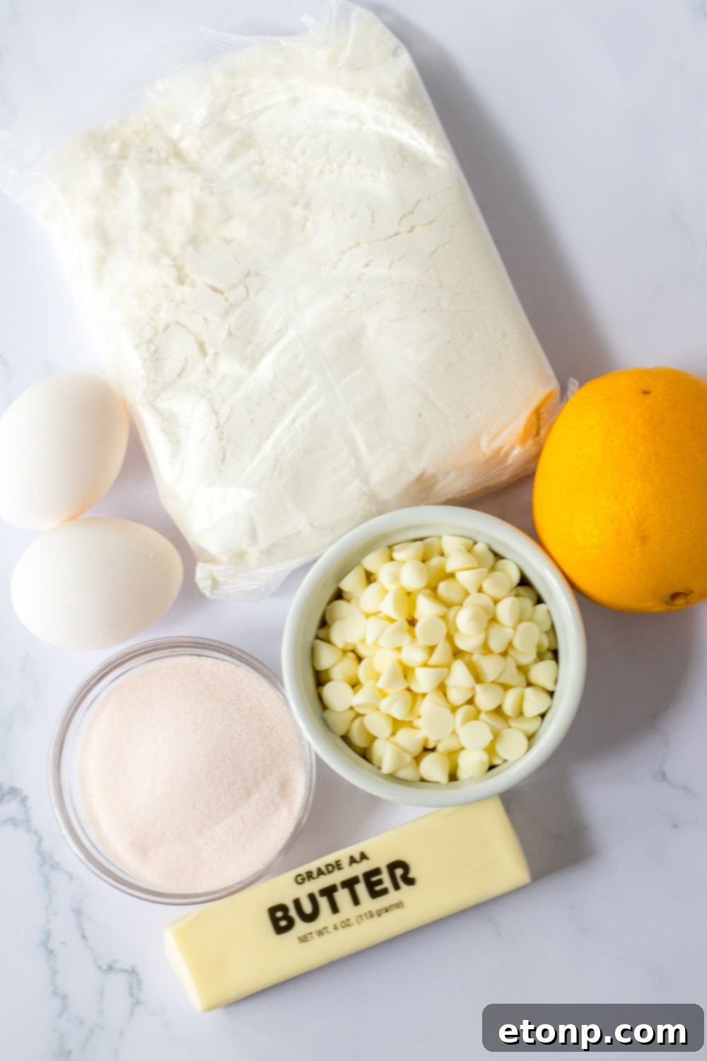 ingredients for orange cookies sitting on a marble table 