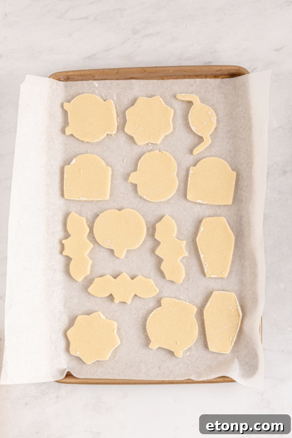Halloween shaped sugar cookies on a baking sheet in raw shapes 
