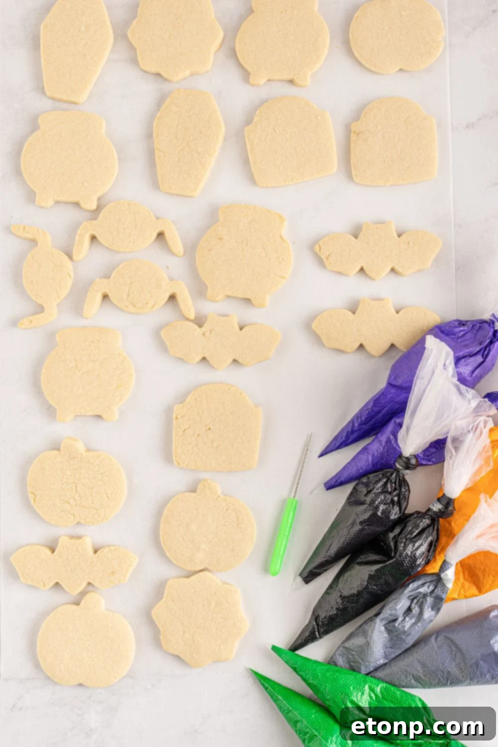 sugar cookies on counter with piping bags of frosting around it 