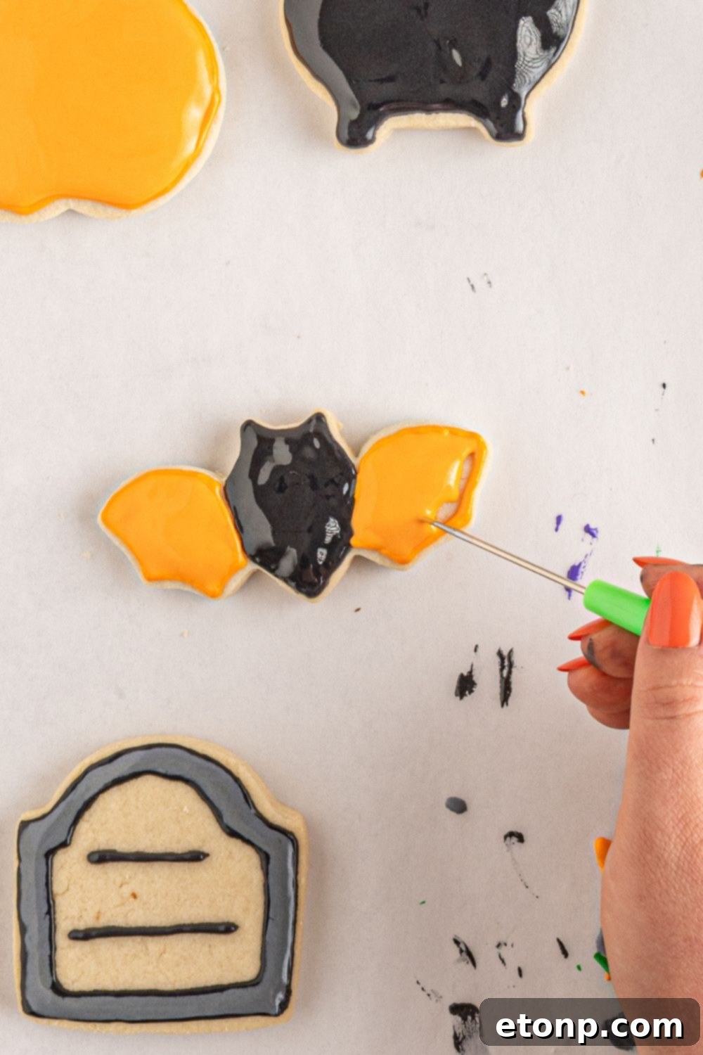spreading the royal icing out on bat cookie 