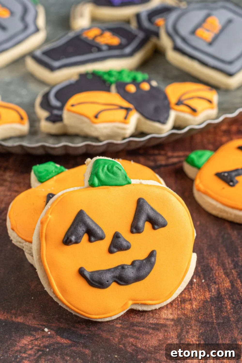 pumpkin cookies on table with a platter of cookies behind it