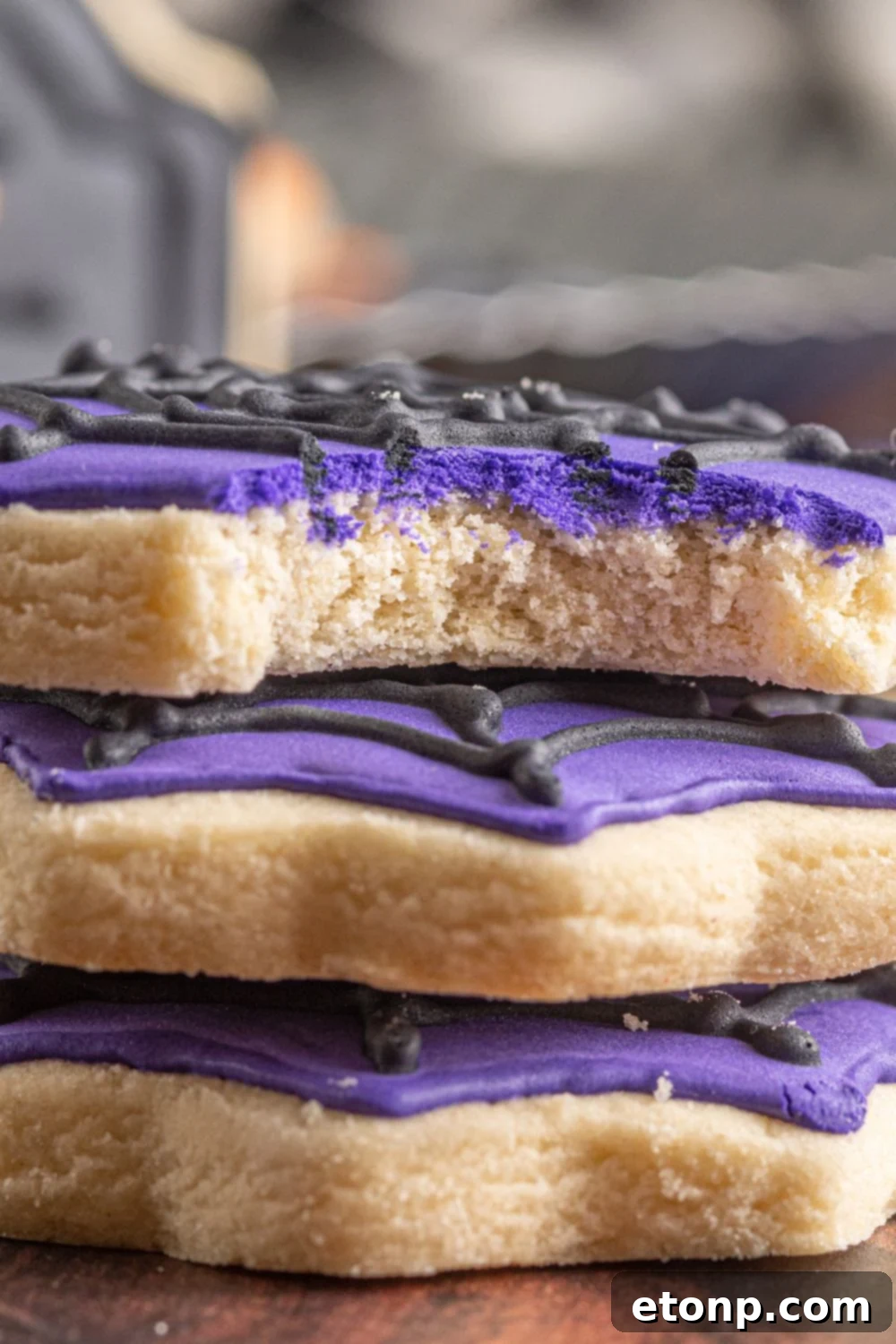 stacked sugar cookies on table with one that has a bite taken out of it