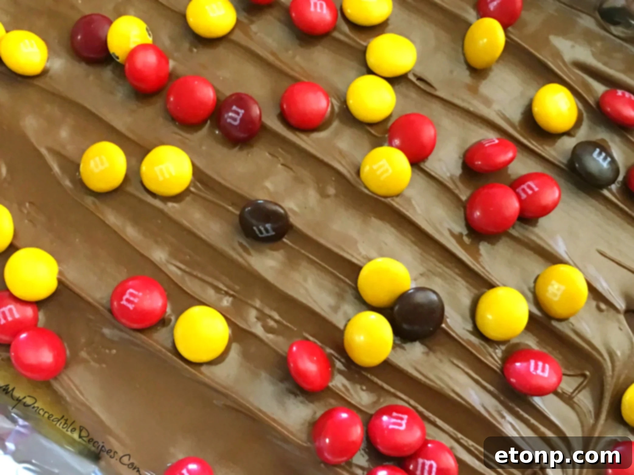 Various colorful candies and nuts adorning the chocolate surface of the toffee
