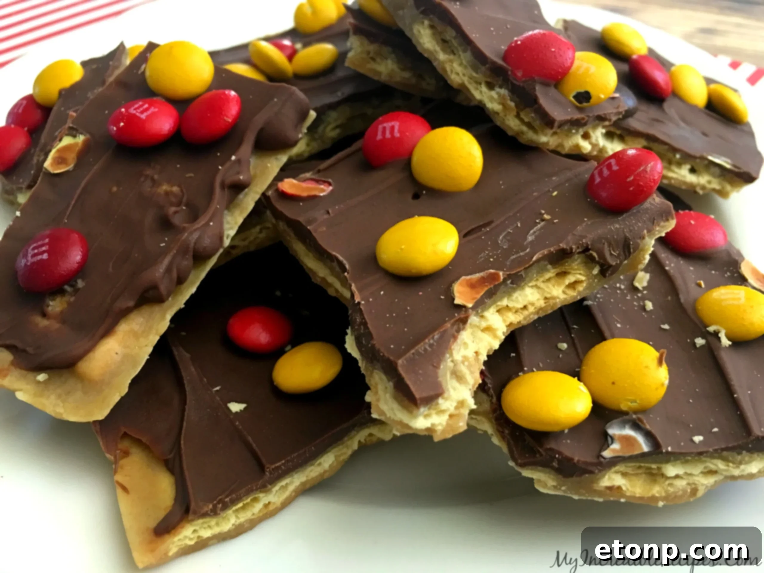 Artfully arranged pieces of saltine cracker toffee, some wrapped for gifting, on a white background