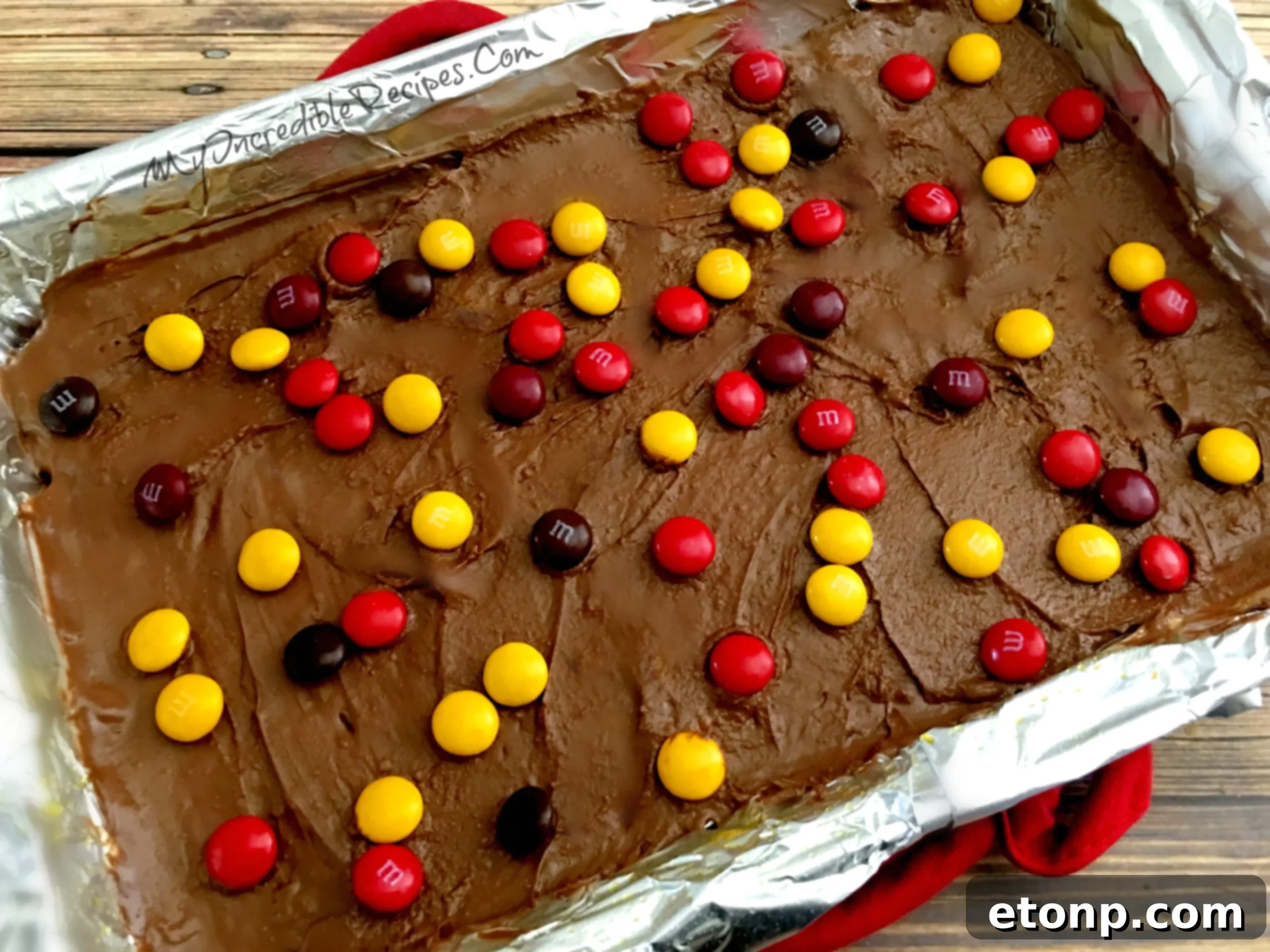 A close-up view of vibrant M&Ms sprinkled over melted chocolate on saltine toffee