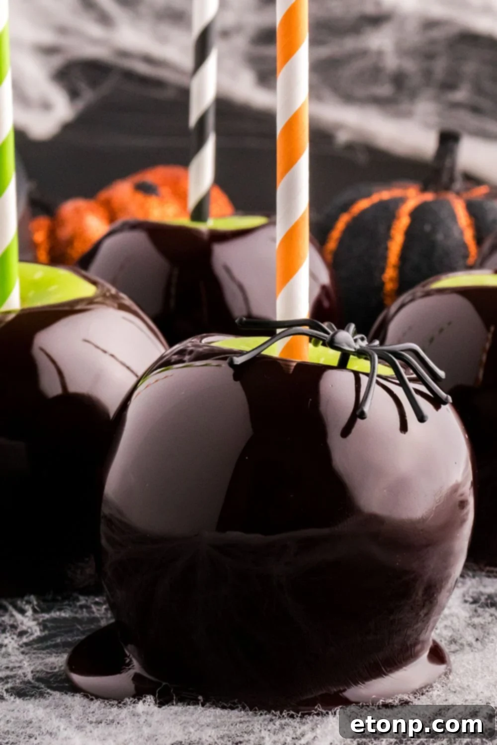 candy apples on table with a candy apple with black spider on it for spooky looks