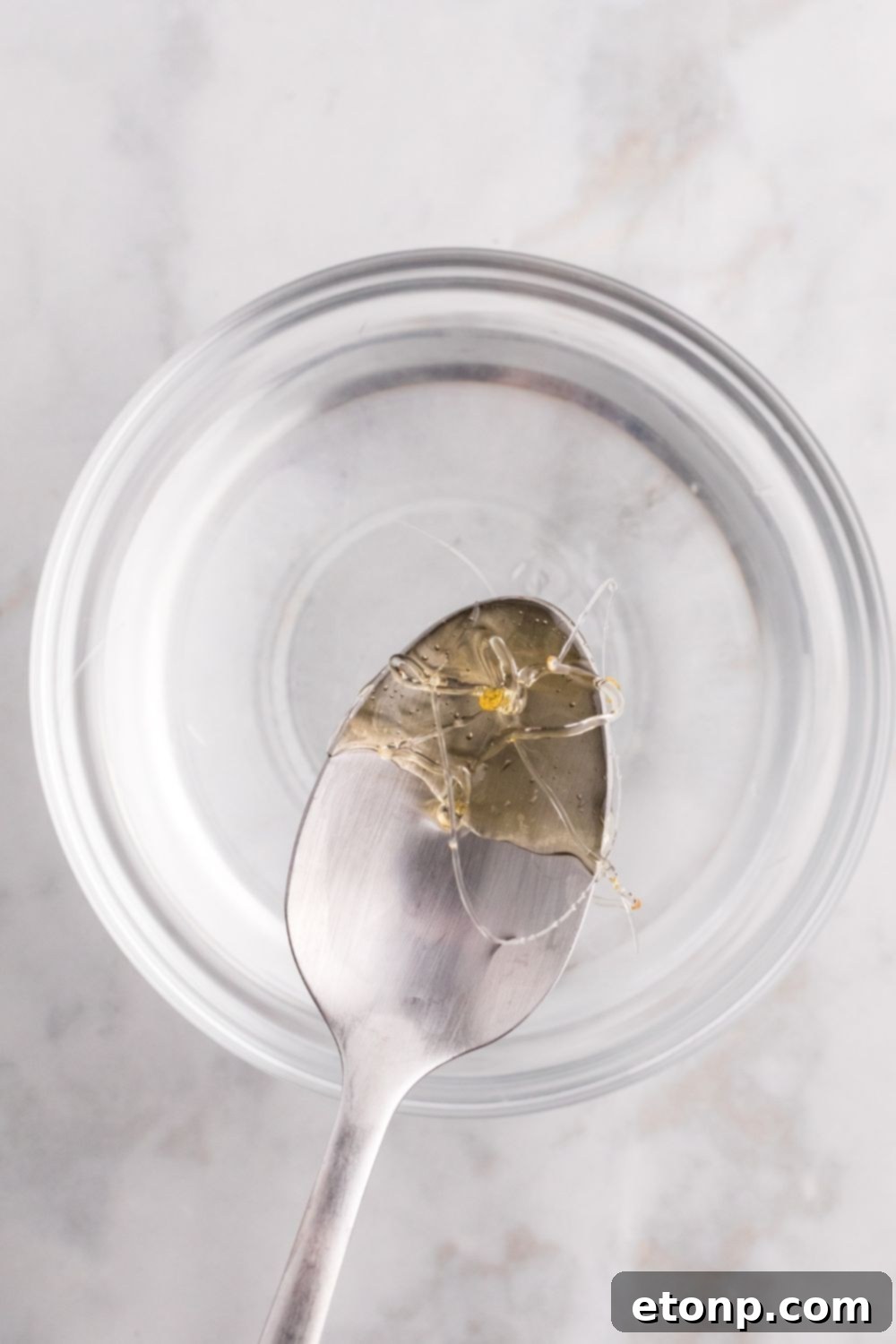 spoon with hardened candy coating on it above a bowl of water 