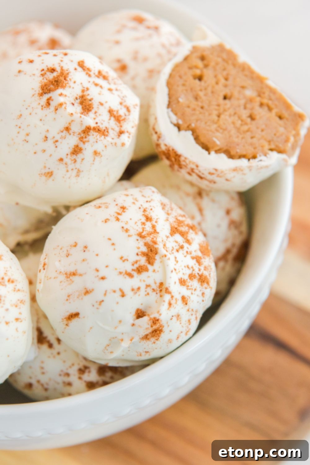 An elegant white bowl filled with white chocolate pumpkin cheesecake bites, perfectly showcased on a table setting.