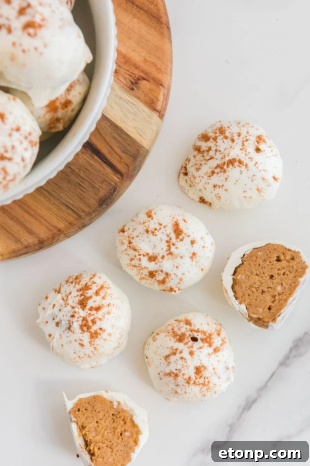 A tray of no-bake pumpkin cheesecake bites on a table, some cut in half to showcase their delightful filling and texture.
