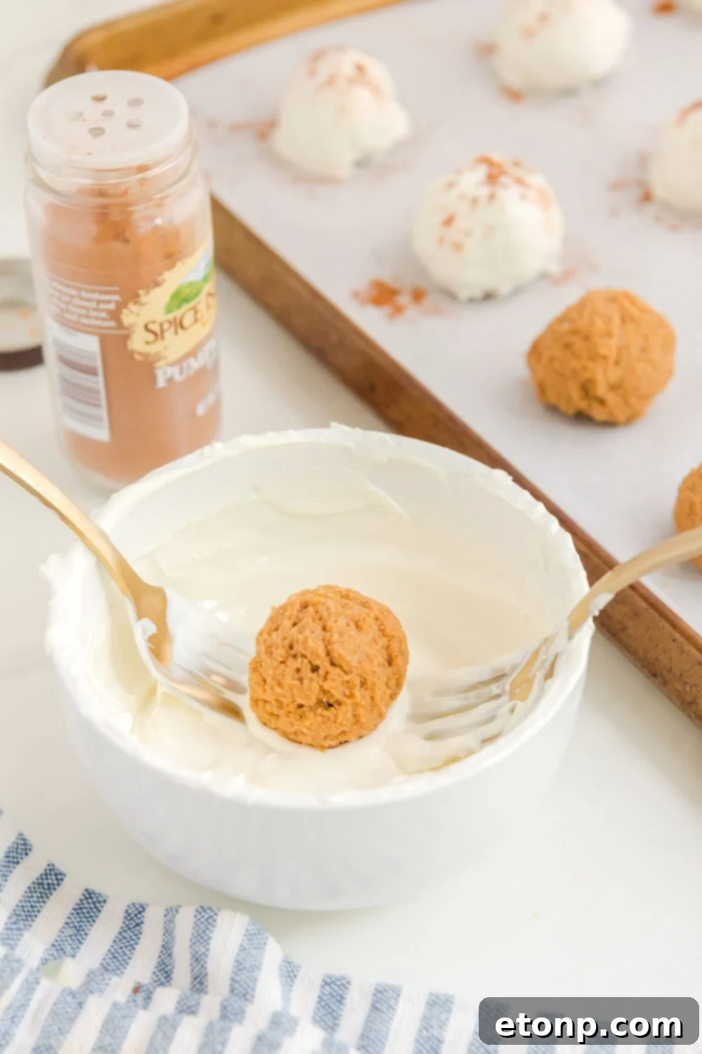 The process of rolling a cheesecake bite in luscious melted chocolate, ensuring an even and complete coating.