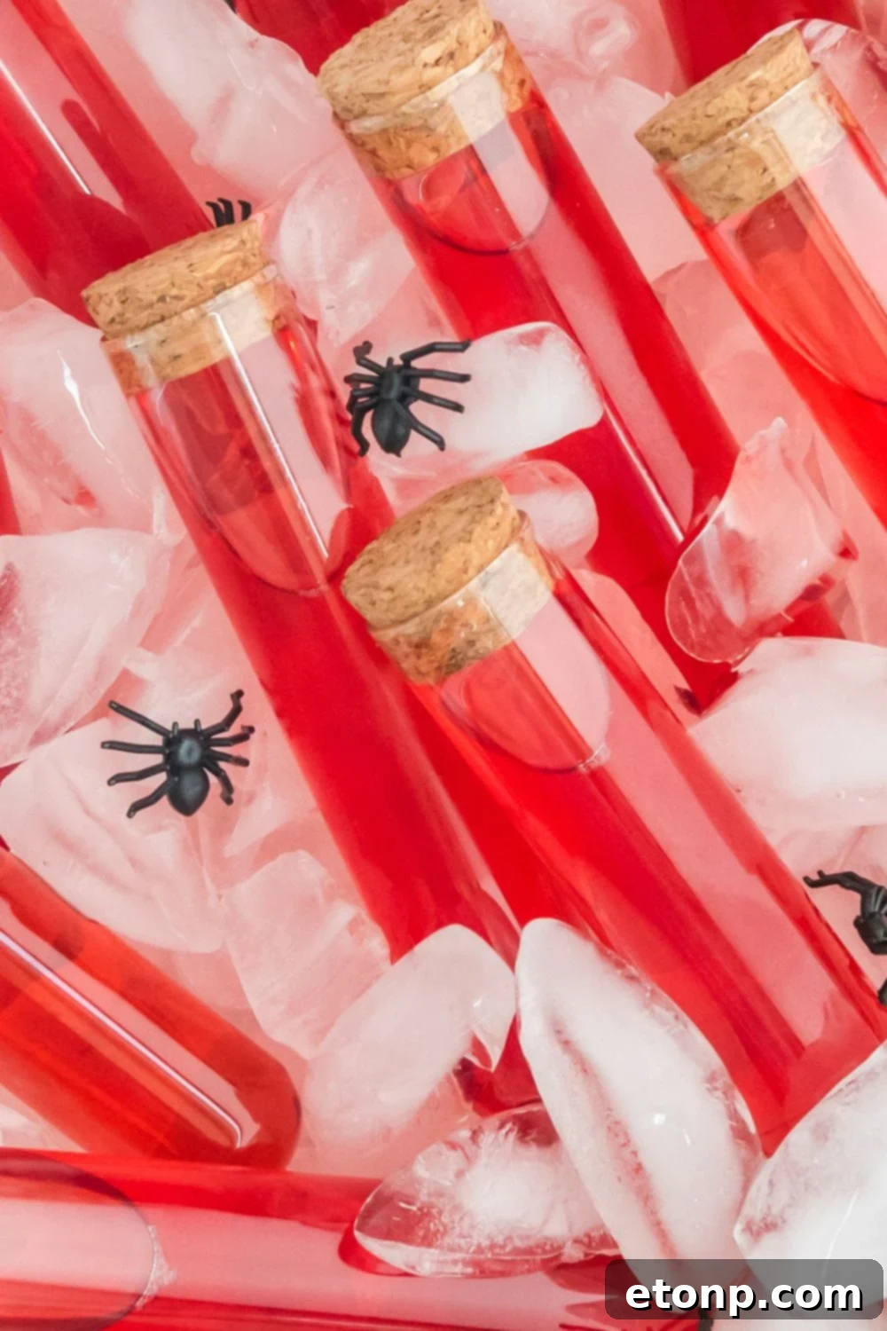 close up of red test tubes in container with ice cubes and fake spiders