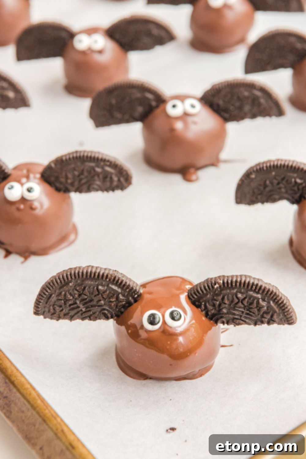 A freshly dipped Bat Oreo Truffle on parchment paper, before adding wings and eyes