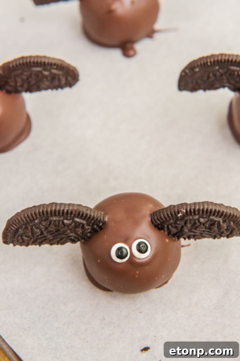 Finished Bat Oreo Truffles resting on parchment paper, showcasing their detailed wings and eyes