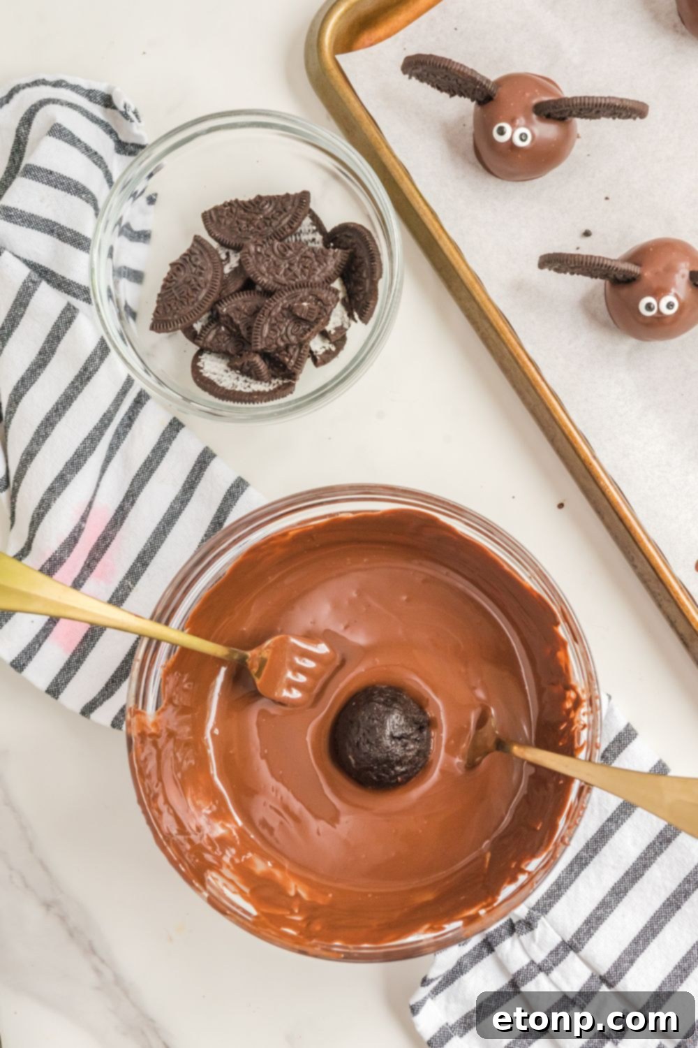 An Oreo ball being carefully dipped into a bowl of melted chocolate
