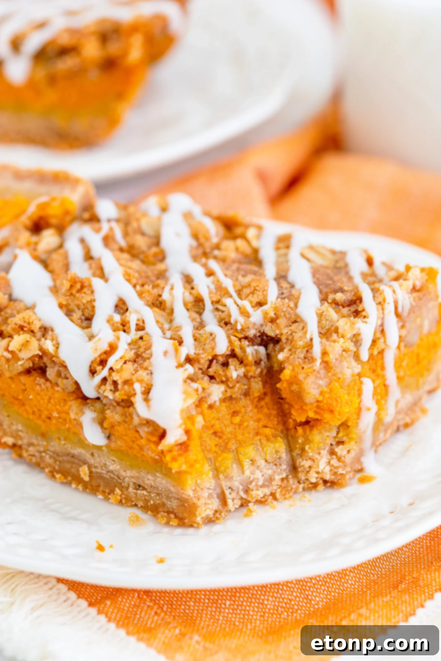 Sweet Autumn Pumpkin Crumble Bars 16 Pumpkin Streusel Bars on a white plate drizzled with glaze