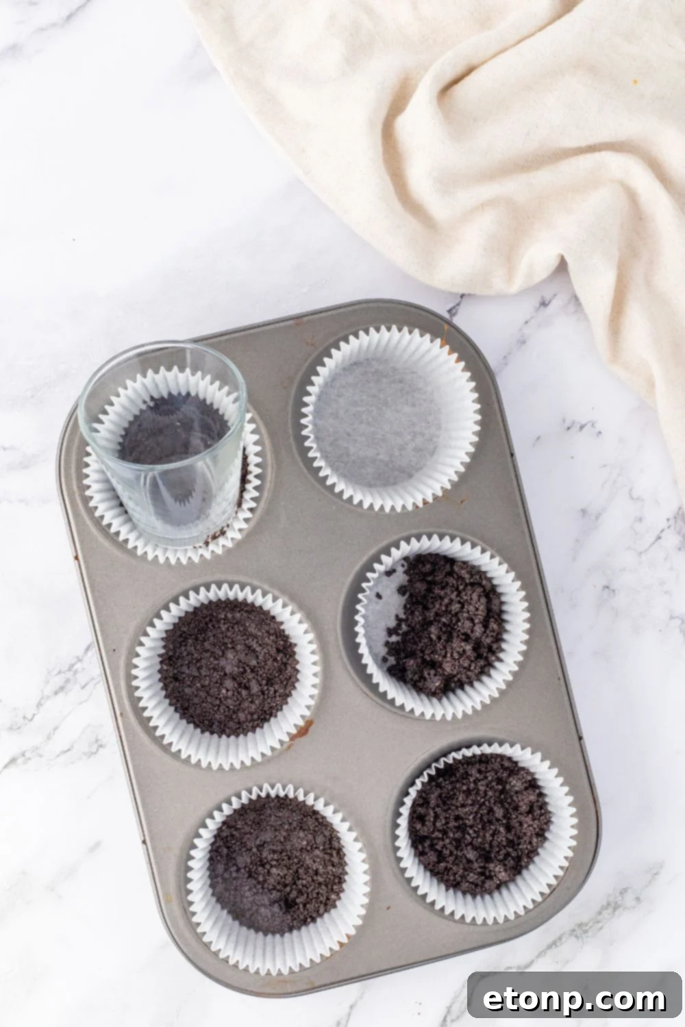 Bite-Sized Peanut Butter Cheesecakes 7 pressing Oreo cookie crust in muffin tin, step 2