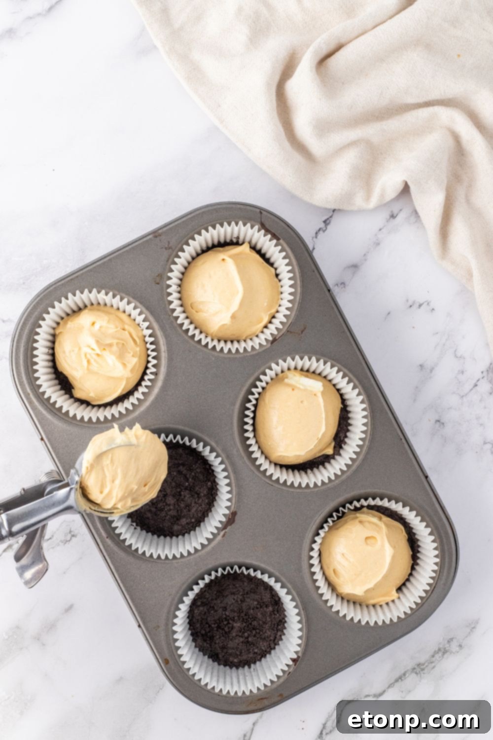 Bite-Sized Peanut Butter Cheesecakes 9 spooning peanut butter cheesecake into pan, step 4