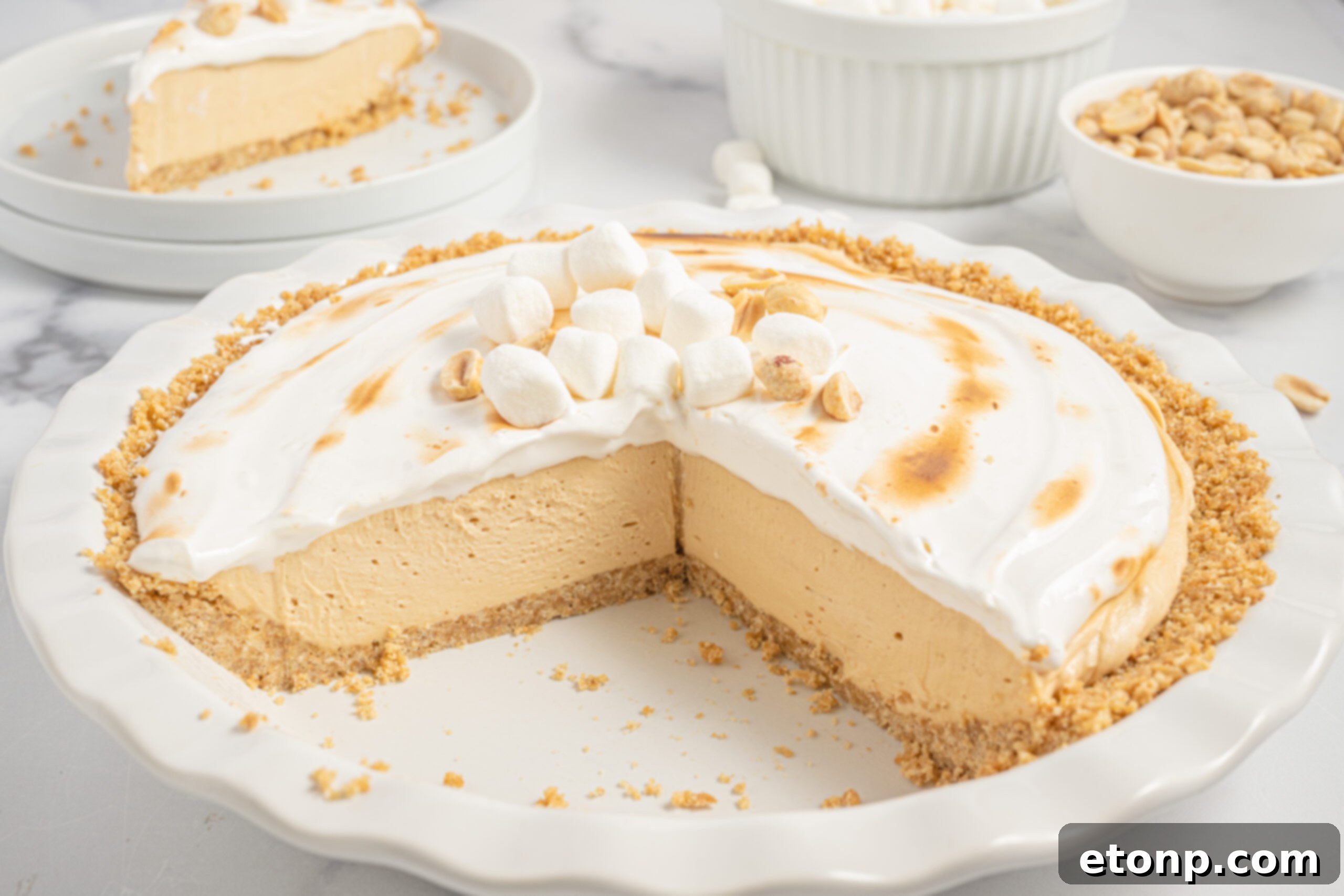 A whole Fluffernutter Pie in a white baking dish with a couple slices missing