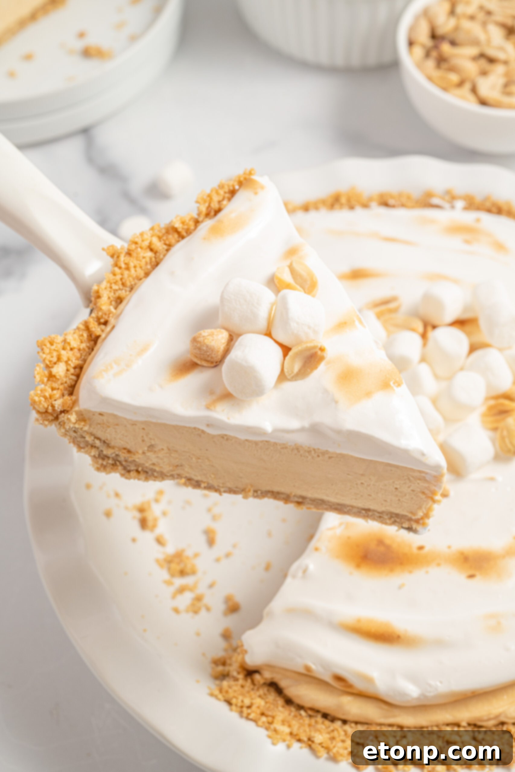 Fluffernutter pie slice being lifting up from the white pie dish, showcasing its layers