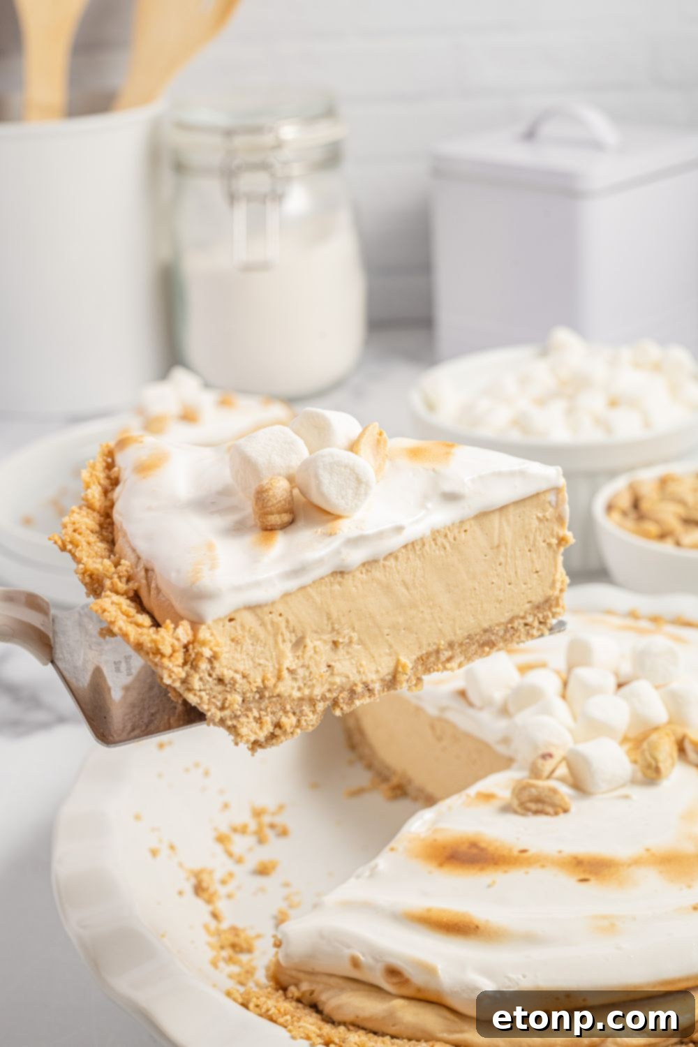 A slice of peanut butter pie with cream cheese on a spatula, showcasing the layers
