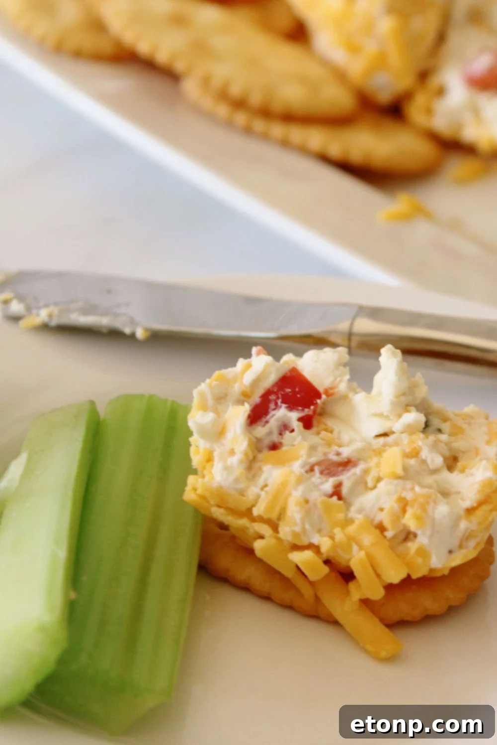 cracker with cheeseball and celery sticks on plate