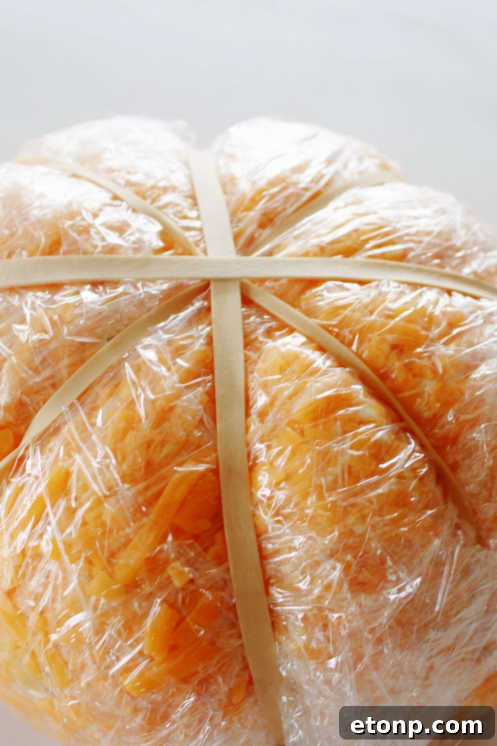 cheeseball wrapped in plastic and rubber bands around it 