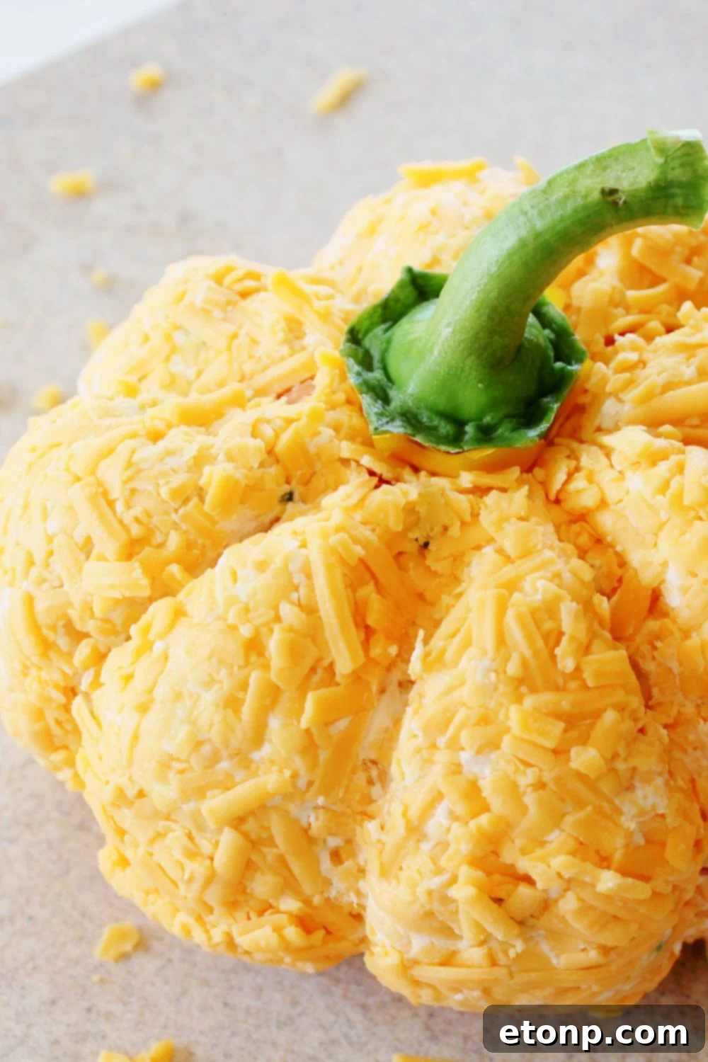 pumpkin shaped cheeseball with a pepper stem placed on top 