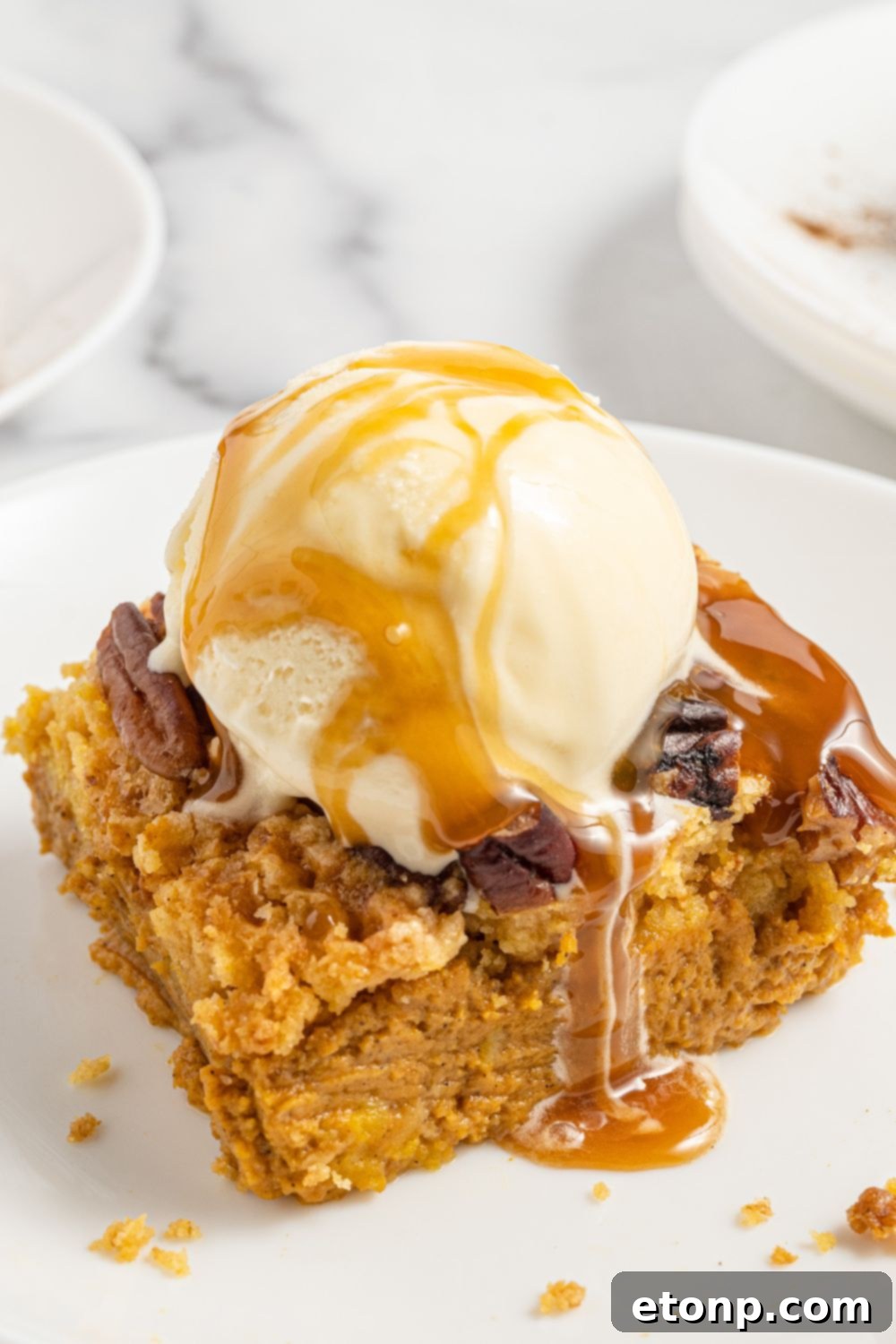 Pumpkin Streusel Cobbler 5 slice of pumpkin cake on plate with scoop of ice cream and caramel sauce on top