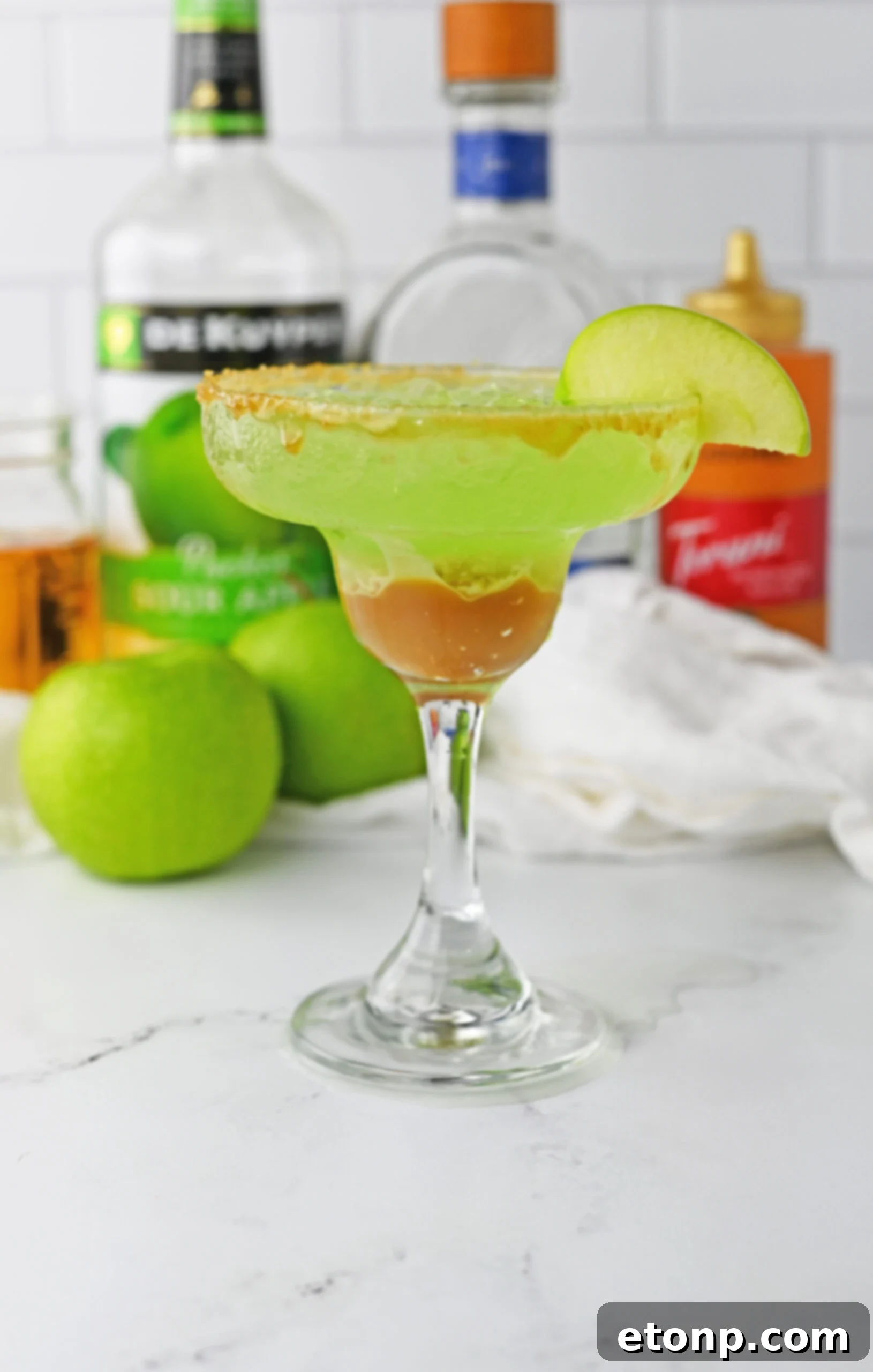 side view of caramel apple drink on table with apples behind it