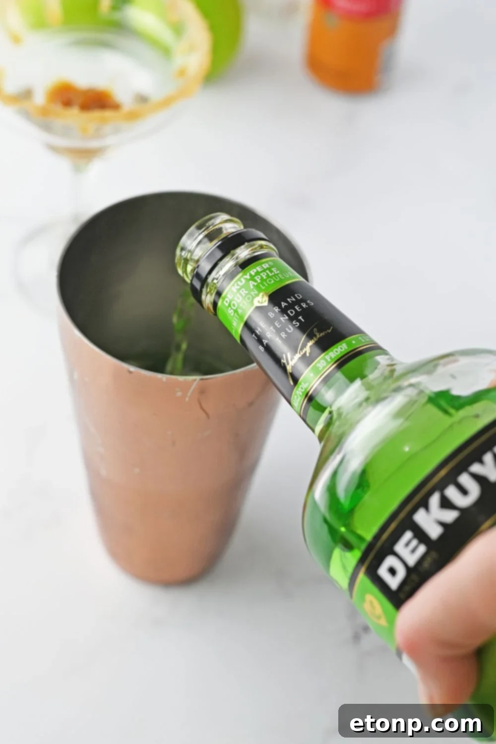 pouring sour pucker into a cocktail shaker 