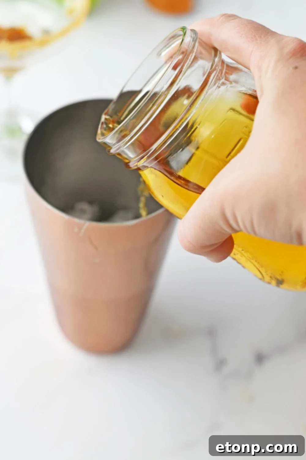 pouring apple juice into a cocktail shaker