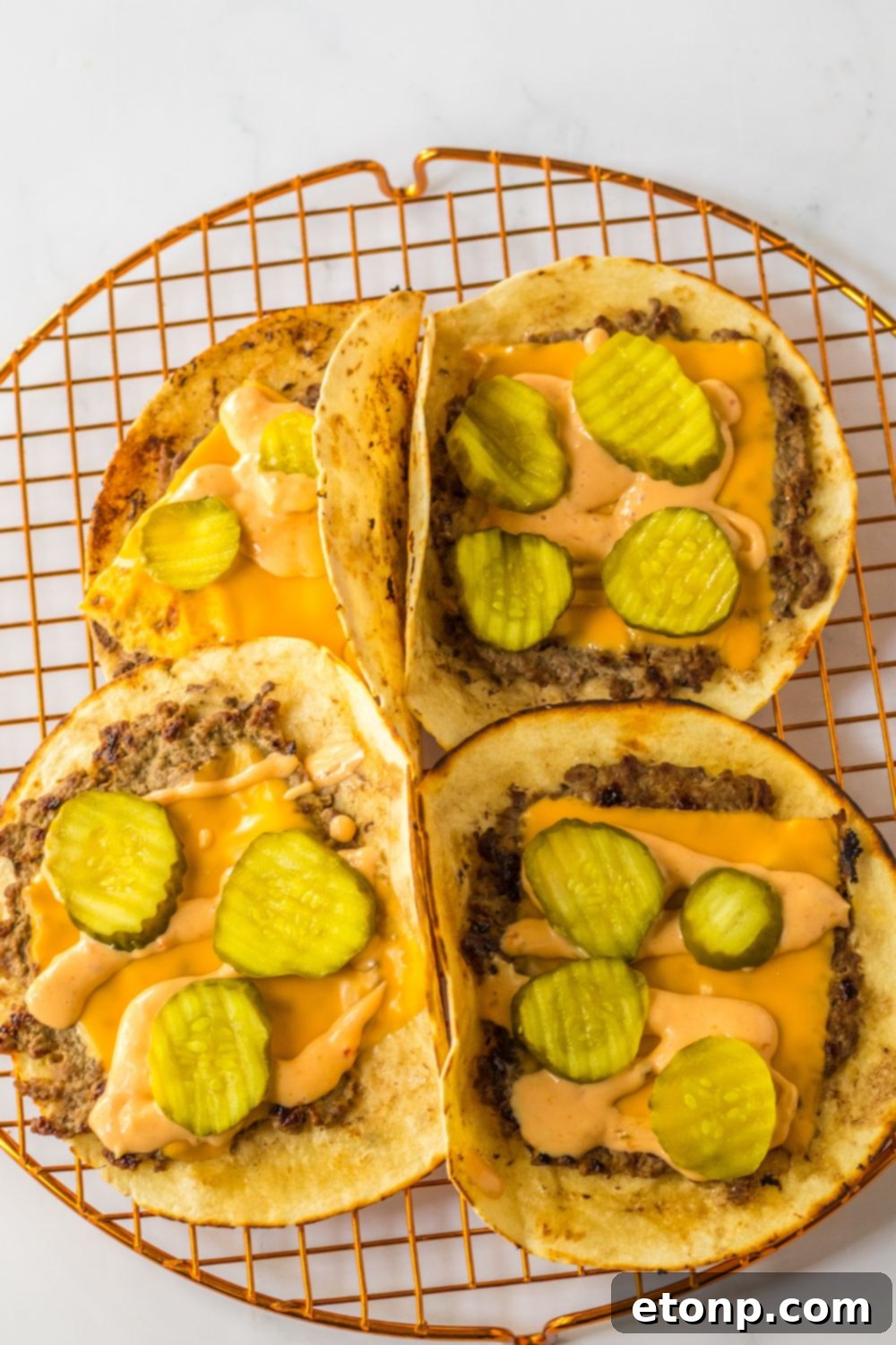 Smash tacos topped with melted cheese and pickles