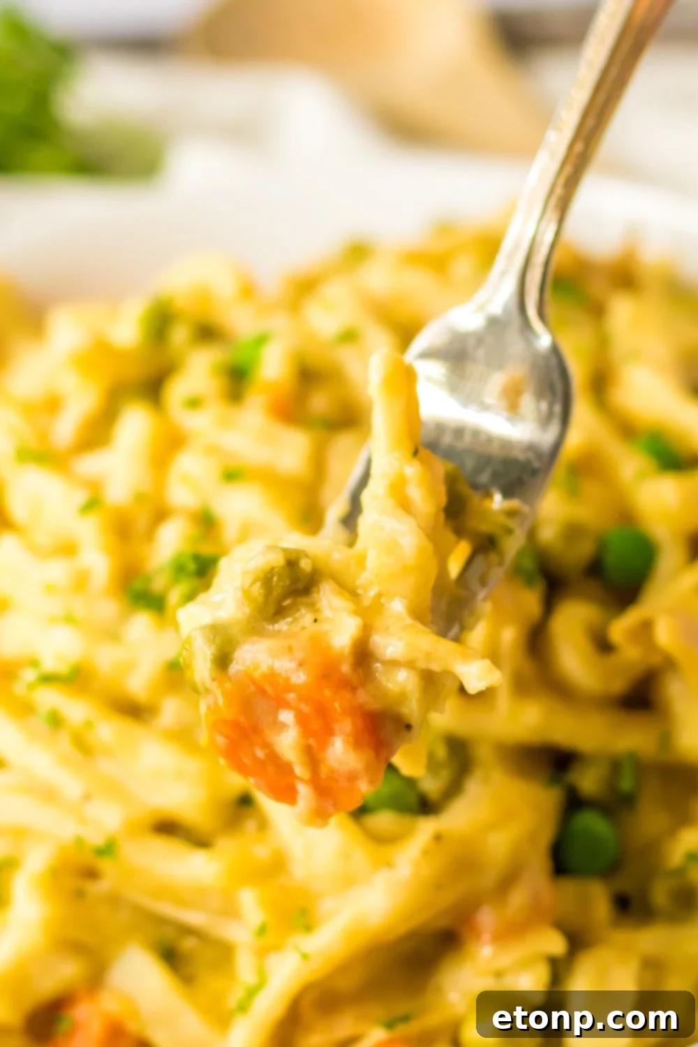fork with chicken and noodles on it above a bowl