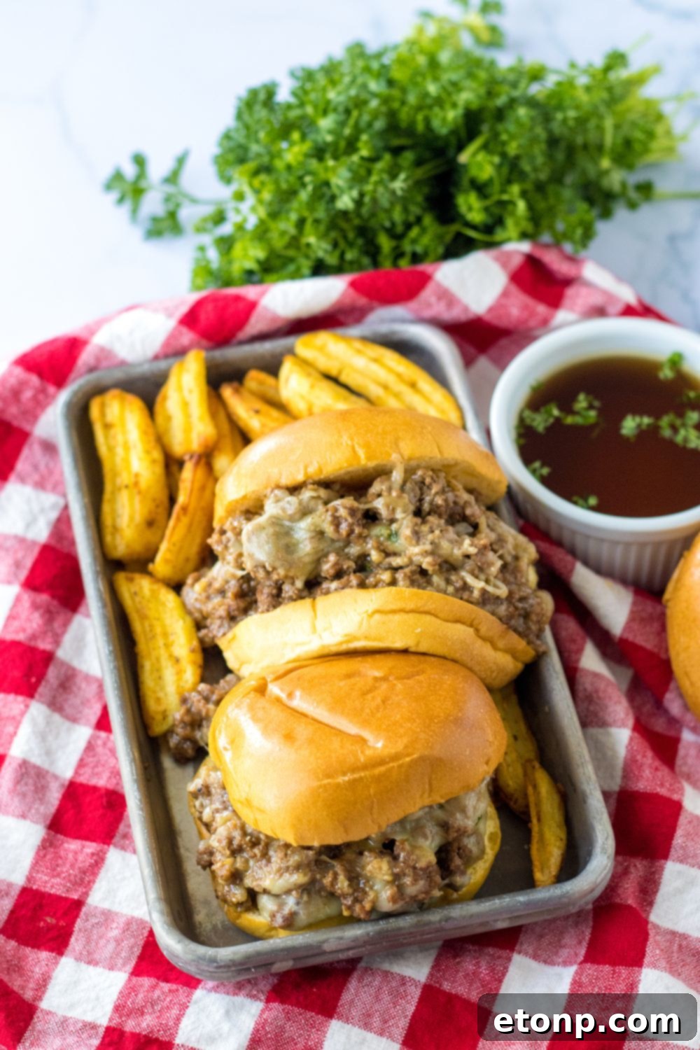 beef au jus sandwiches on a tray with red plaid napkin under it
