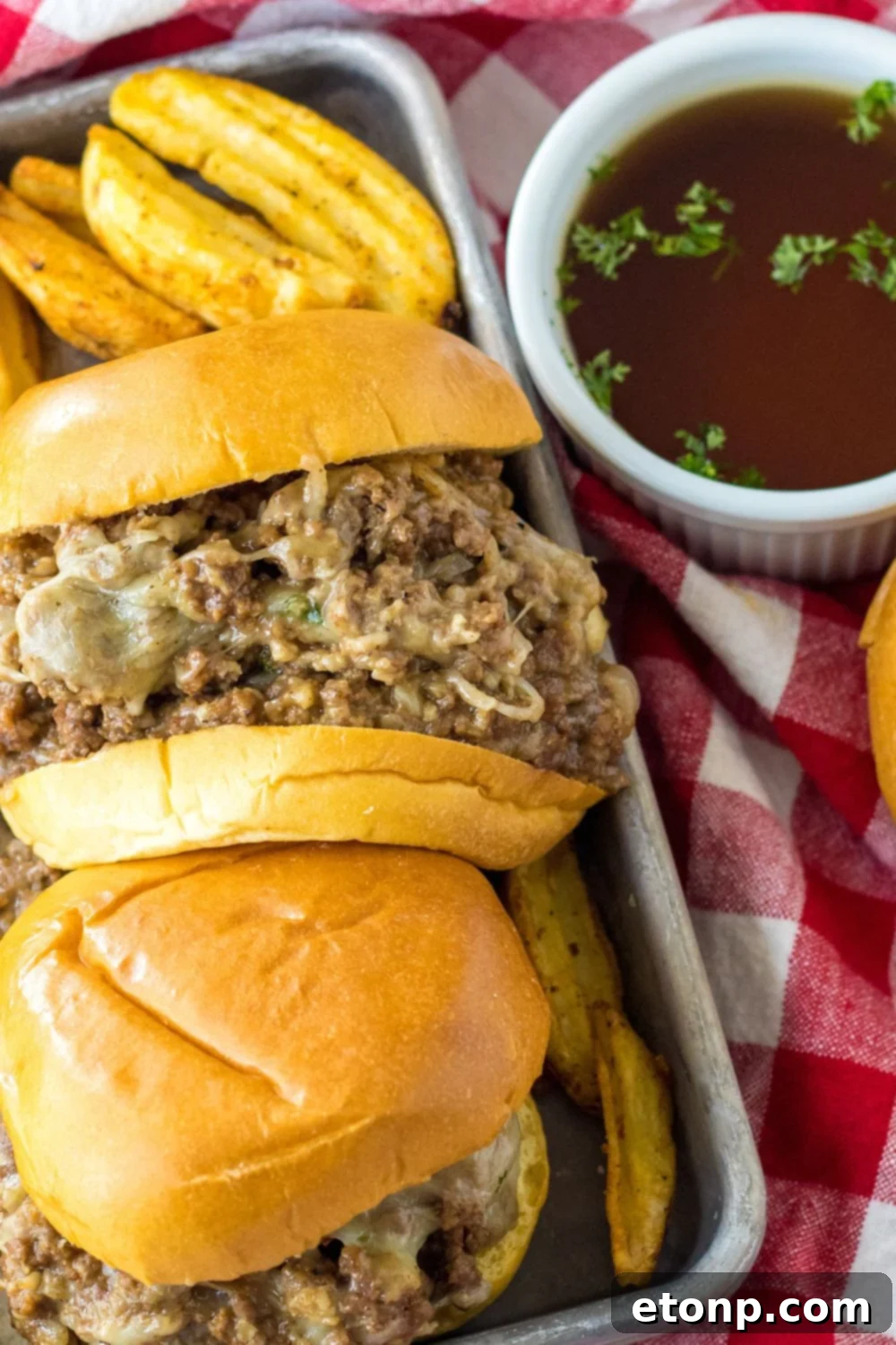 french dip sauce in bowl and sandwiches on side