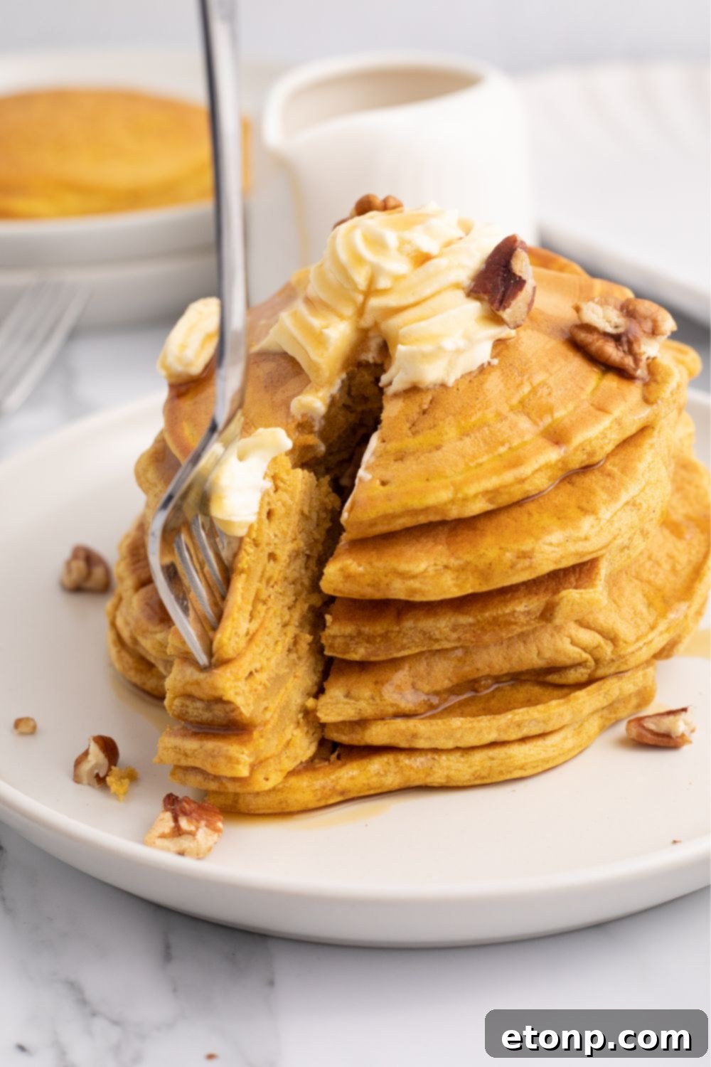 A slice of pumpkin pancake next to a stack on a plate