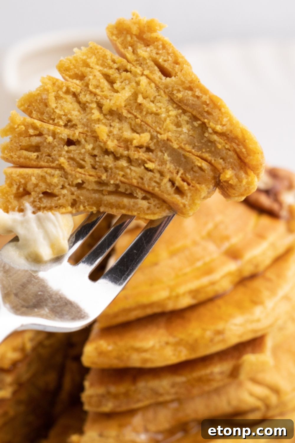 A close-up of a bite of pumpkin pancake, showcasing its texture
