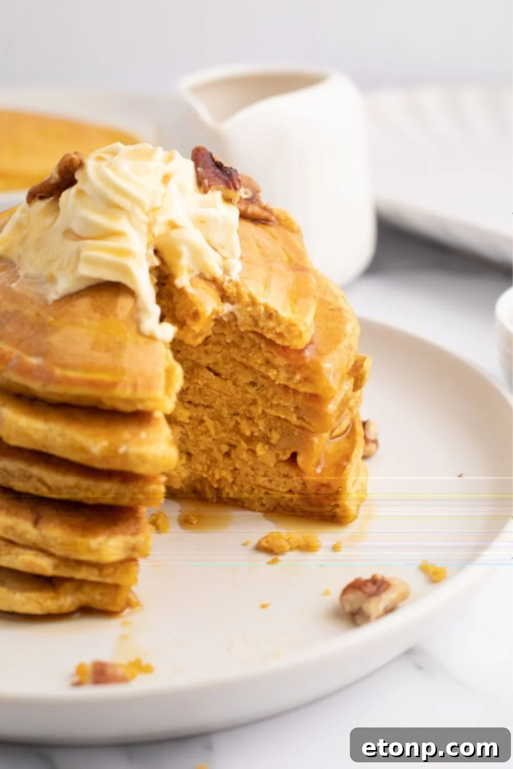 Two plates of perfectly cooked pumpkin pancakes, garnished and stacked